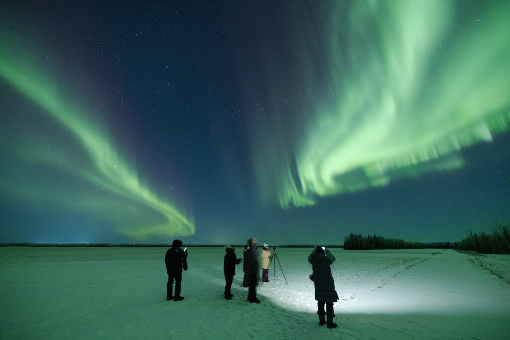 Night photography showing how headlamps, flashlights, and cell phone screens create disruptive light pollution during aurora viewing
