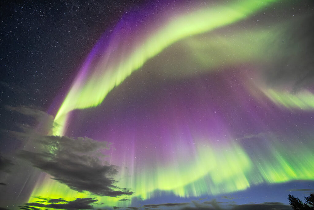 Fairbanks Alaska aurora capital with vivid northern lights over a viewing area showing why it is the best place for Fairbanks northern lights tonight