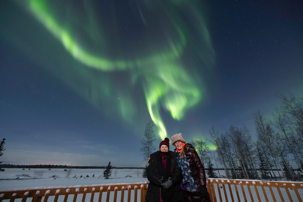 Small group northern lights tour watching aurora from private lodge deck near Fairbanks with dark skies and no light pollution